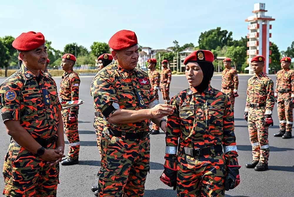 Nordin (dua dari kiri) melekatkan ‘Patch’ STORM kepada pelatih, Saredah pada Majlis Tamat Latihan Kursus Asas Pasukan Khas Operasi, Taktikal dan Penyelamat Malaysia (STORM), JBPM Siri 1/2024 di Akademi Bomba dan Penyelamat Malaysia Wilayah Timur, Wakaf Tapai, pada Rabu. Foto Bernama