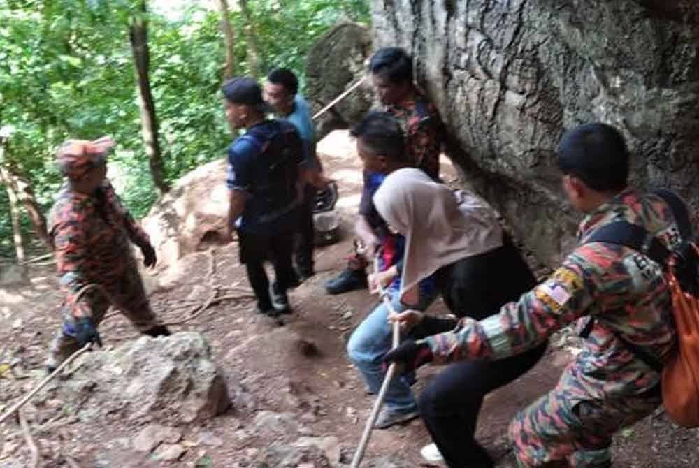 Salah seorang mangsa (dua dari kanan) yang tersesat ketika mendaki Bukit Kodiang dibawa turun dengan bantuan anggota bomba dan malim gunung.