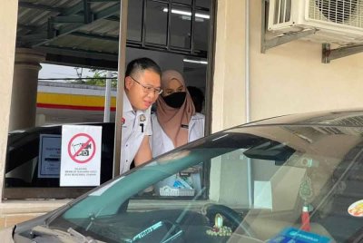 Tian Soon berkata sesuatu kepada orang ramai yang menggunakan khidmat pandu lalu bagi mengambil ubat.