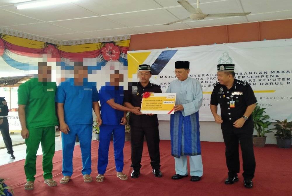 Mohd Zahidi (dua dari kanan) menyerahkan replika cek sumbangan sempena Majlis Penyerahan Sumbangan Makanan Kepada Prospek Bersempena Sambutan Ulang Tahun Hari Keputeraan Duli Yang Maha Mulia Paduka Seri Sultan Perak Darul Ridzuan di Kelab Golf Pusat Koreksional Kamunting di sini pada Jumaat.