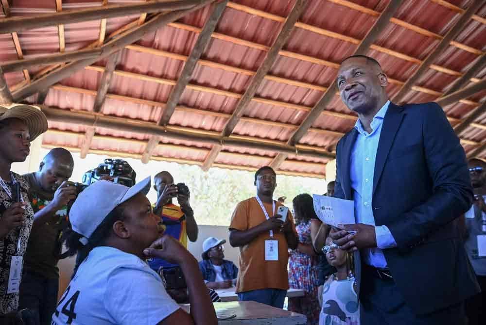 Duma Boko (kanan) selepas menerima kertas undi daripada pegawai pilihan raya di Gaborone pada 30 Oktober, semasa pilihan raya umum Botswana. Foto AFP