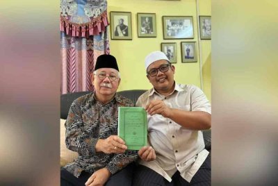 Jamaluddin (kiri) menunjukkan kitab Pohon Agama yang boleh dijadikan panduan ilmu asas tauhid.