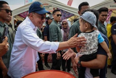 Anwar (kiri) bertegur sapa dengan seorang kanak-kanak ketika melakukan lawatan ke gerai jualan selepas merasmikan Karnival Generasi Ada Idea (Gen-AI) di Gravitas pada Sabtu. Foto Bernama