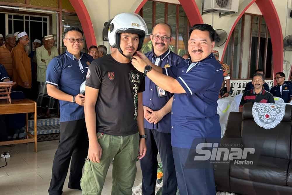 Muhammad Kifli (kanan) yang menyampaikan topi keledar kepada penduduk. Foto Sinar Harian/ADILA SHARINNI WAHID.