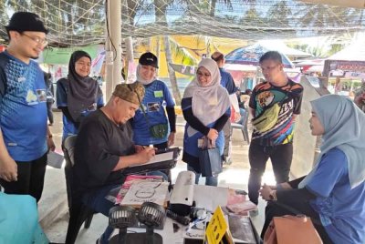 Muhammad Izzat (kiri) melukis wajah pelanggan yang menghadiri program di Pulau Sri Tanjung.