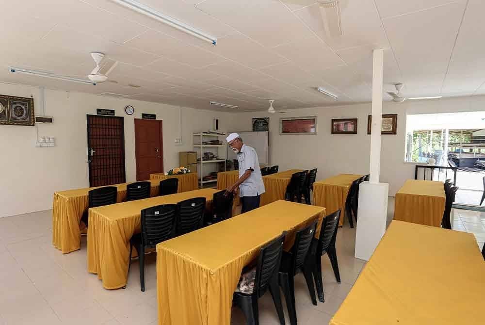 Idris menyusun kerusi di Balai Lintang yang dibaik pulih dengan peruntukan program Kampung Angkat Madani, Jabatan Audit Negara. Foto Bernama