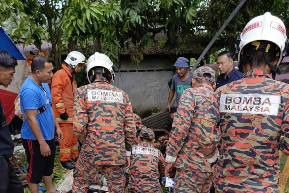 Anggota BBP Taman Tas membantu menyelamatkan mangsa yang cedera susulan kejadian sebuah lori tanah terbabas dan merempuh warung di tepi jalan di Batu 8, Jalan Gambang di sini, petang Isnin. Foto JBPM Pahang.