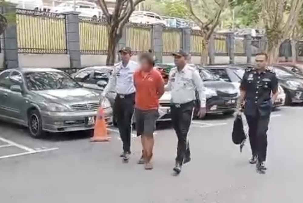 Tertuduh diiriingi anggota polis sebaik tiba di perkarangan mahkamah.