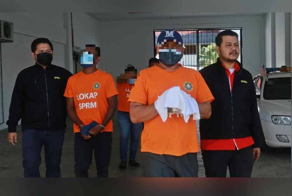 Aktivis politik tersebut (dua dari kanan) dan dua lagi suspek ketika diiringi anggota SPRM semasa keluar dari pekarangan lokap Mahkamah Alor Setar pada Selasa.