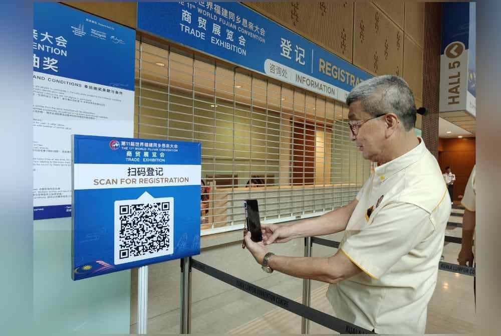 Hock San membuat imbasan kod QR untuk pendaftaran Konvensyen Dunia Fujian ke-11 di KLCC.