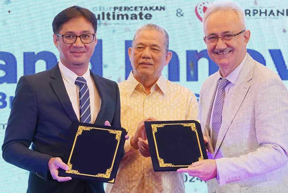 Azizi (kiri) bertukar memorandum perjanjian dengan Abdullah Yasir (kanan) disaksikan oleh Fadillah (tengah) pada majlis Menandatangani Perjanjian Persefahaman antara Ultimate Print Sdn. Bhd dan Darphane pada Khamis.