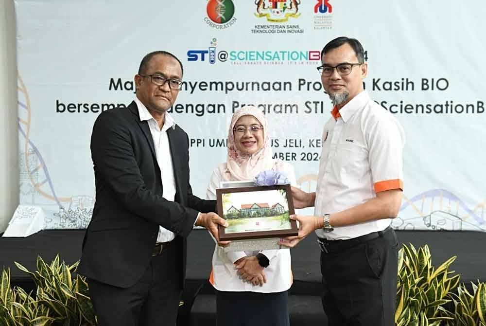 Penyampaian cenderamata kepada Mohd Khairul Fidzal (kanan) sambil diiringi Ruziah (tengah).