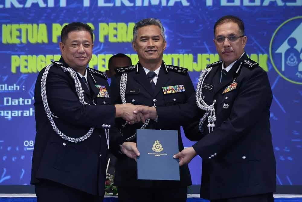 Mohd Shuhaily (tengah) menyaksikan pertukaran dokumen serah terima tugas Ketua Polis Perak antara Azizi (kiri) kepada Zulkafli (kanan) yang memangku jawatan itu selepas Azizi bersara wajib.