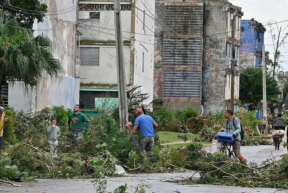 Penduduk membersihkan kawasan kediaman mereka selepas kejadian Taufan Rafael di Artemisa, Cuba pada Khamis - Foto: AFP