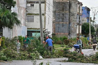 Penduduk membersihkan kawasan kediaman mereka selepas kejadian Taufan Rafael di Artemisa, Cuba pada Khamis - Foto: AFP