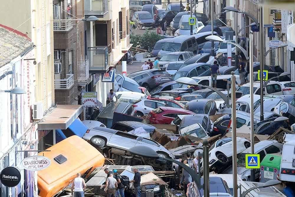 Orang ramai melihat kenderaan yang dihanyutkan banjir di jalan raya sekitar Sedavi, selatan Valencia. - AFP