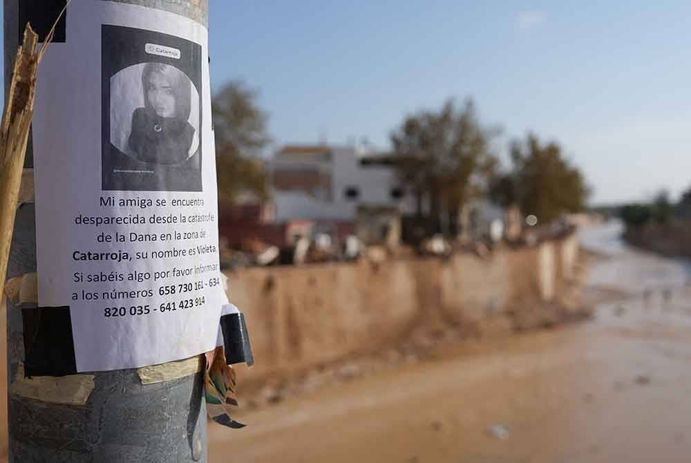 Saudara-mara mangsa menampal poster anggota keluarga mereka yang hilang di Catarroja selepas banjir dahsyat melanda wilayah itu.