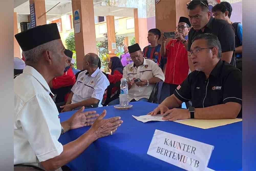 Adly (kanan) mendengar aduan daripada pesara tentera semasa Program Veteran Desa Madani (VDM) di Sekolah Kebangsaan Bechah Laut, Tanah Merah pada Sabtu.