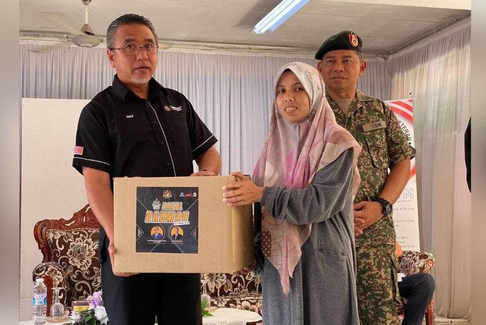 Adly (kiri) menyampaikan sumbangan kepada penerima semasa Program Veteran Desa Madani (VDM) di Sekolah Kebangsaan Bechah Laut, Tanah Merah pada Sabtu.