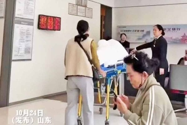 Keluarga lelaki ini hadir ke bank dengan menggunakan katil hospital untuk pengesahan identiti bagi pengeluaran wang. - Agensi