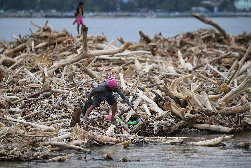 Seorang lelaki mengutip barangan yang hanyut di celah serpihan kayu selepas TaufanTrami melanda bandar Laurel town, wilayah Batangas. Foto AFP