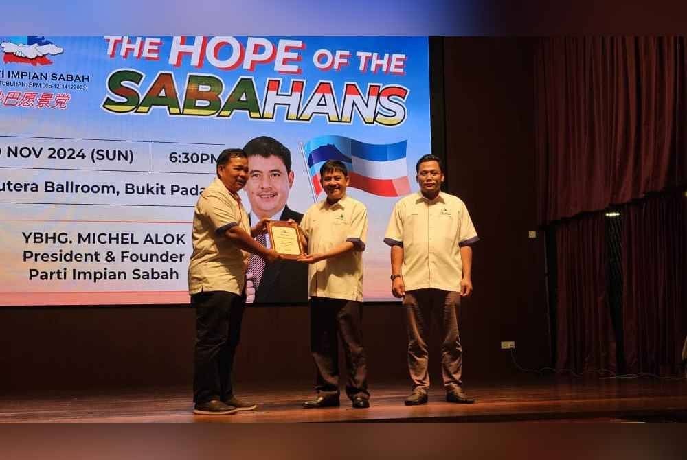 Michel (tengah) menyerahkan MoU kepada calon yang dipilih untuk bertanding PRN Sabah dalam majlis makan malam amal di Kota Kinabalu.