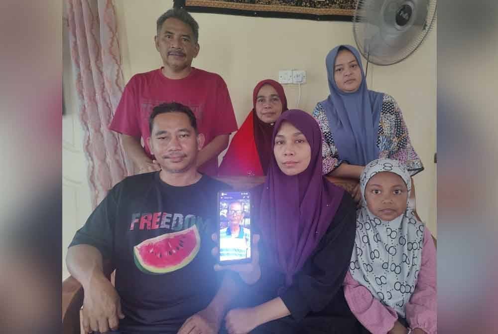 Noraslinda (duduk dua dari kanan) bersama ahli keluarga menunjukkan gambar Allahyarham bapanya yang maut akibat kemalangan pada Isnin.