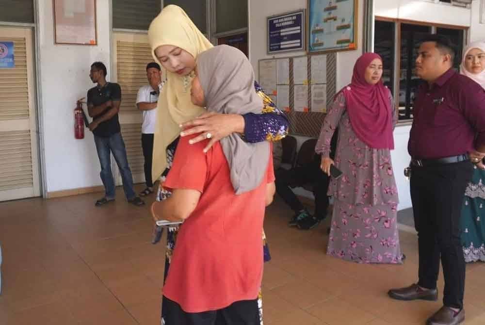 Faridah (kiri) menenangkan Norazilah ketika menziarahi keluarga itu di Hospital Hulu Terengganu.