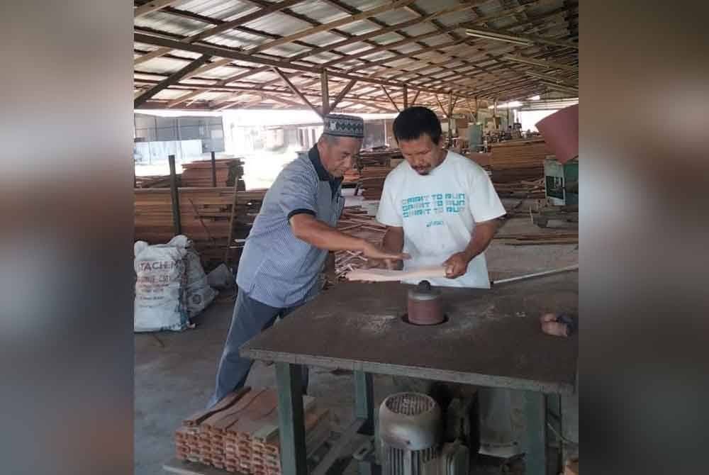 Mohamad (kiri) memberi tunjuk ajar menggunakan isyarat tangan kepada seorang peserta Proka