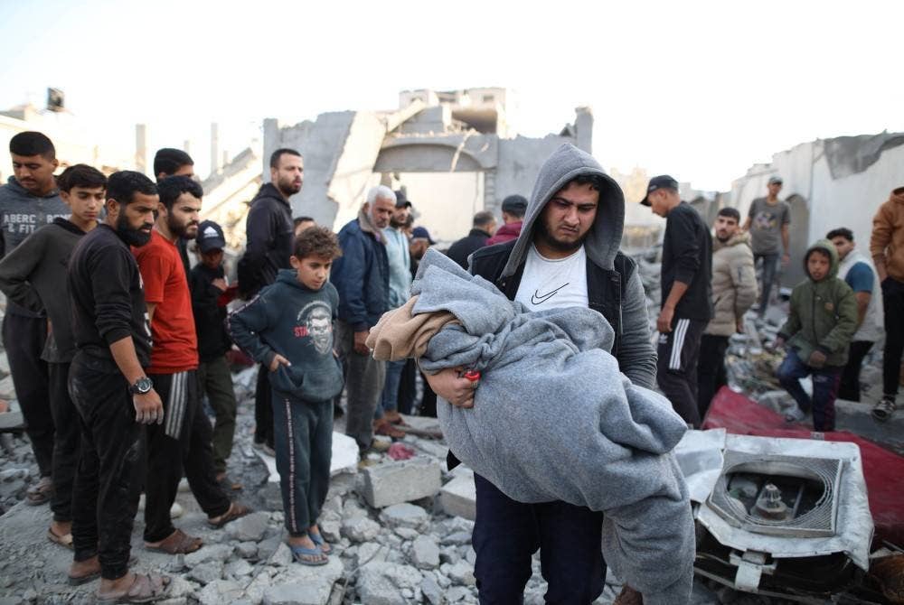 Seorang lelaki bawa mayat mangsa di sebuah bangunan yang musnah dalam serangan udara Israel di kem Nuseirat, tengah Semenanjung Gaza. Foto Xinhua