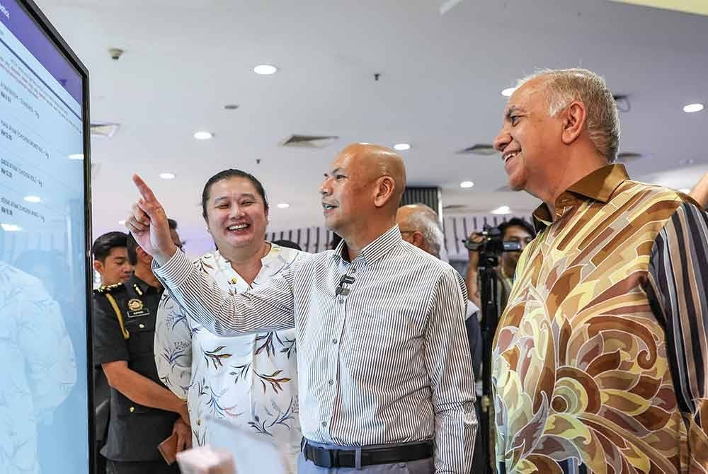 Armizan melihat skrin digital yang memaparkan aplikasi Price Catcher pada majlis menandatangani memorandum persefahaman perkongsian data harga antara KPDN dengan Mydin dan Redtick di Mydin, USJ 1 hari ini - Foto: Bernama