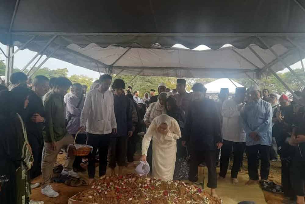 Toh Puan Na'imah menyiram air mawar ke pusara Allahyarham.