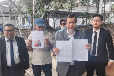 Zulkarnain (dua dari kanan) menunjukkan laporan yang dibuat beliau di Balai Polis Sri Petaling, pada Khamis.