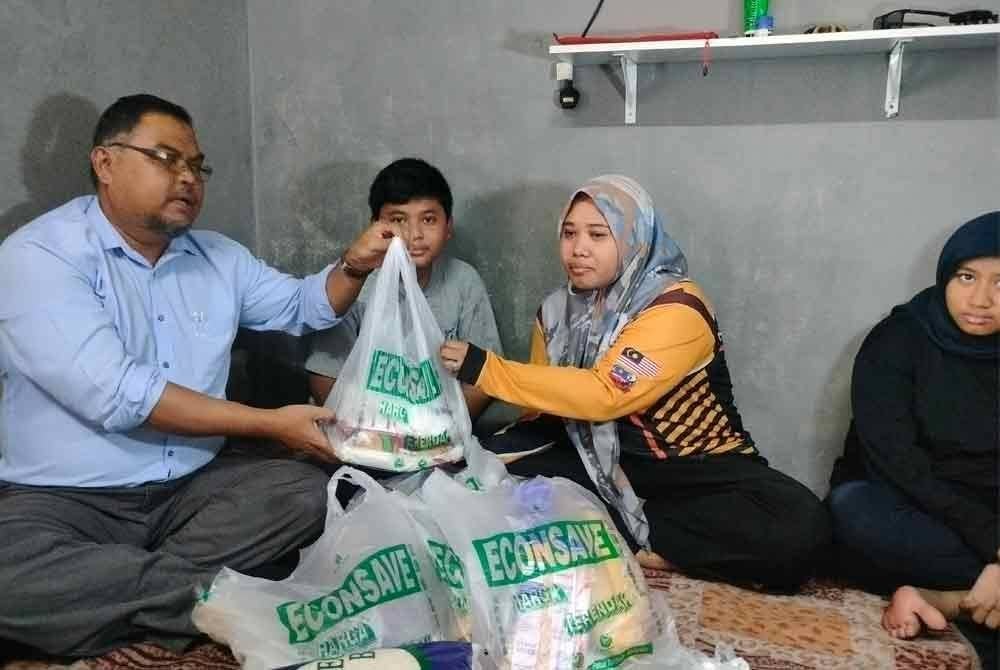 Norzainizah (dua dari kanan) menerima sumbangan daripada Mas Imran (kiri) di Kampung Melayu Majidee pada Jumaat.