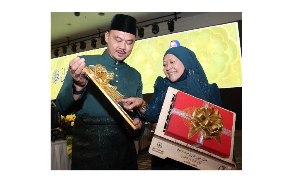Roslan menunjukkan plak Anugerah Anugerah Zaid bin Thabit kepada isterinya, Hazimah Samin.