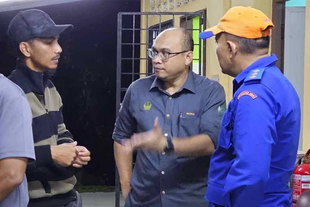 Nazrul Fazami (dua dari kanan) berada di Unit Forensik Hospital Kampar susulan kejadian kepala air meragut nyawa tiga pegawai dan kakitangan JKR.