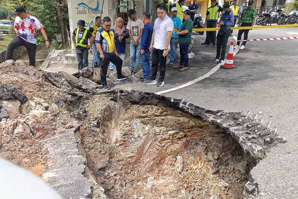 Mohamad Salzeli (kiri) dan Chee Yee melihat lubang benam sedalam dua meter di depan Balai Polis Ayer Keroh pada Sabtu.