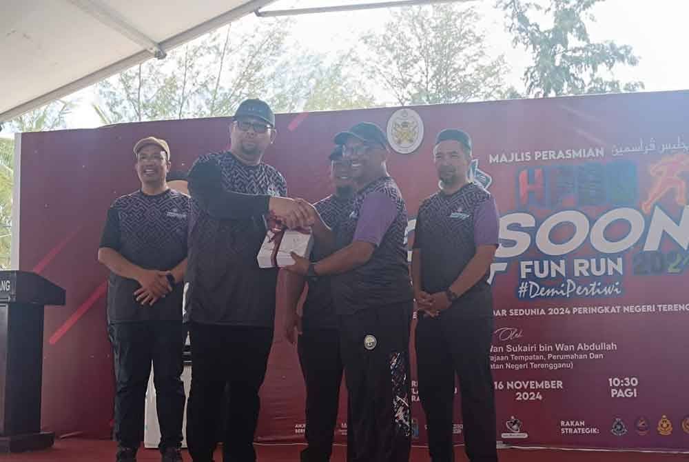 Hassan (kiri) menyampaikan cenderahati kepada salah seorang peserta ketika Sambutan HPBS 2024 Peringkat Negeri Terengganu di Taman Rekreasi, Pulau Kekabu