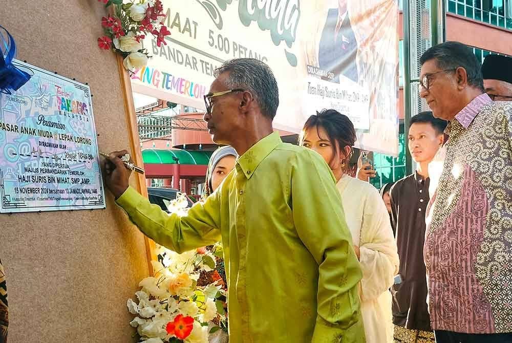 Suris (kiri) menandatangani plak perasmian program tersebut.