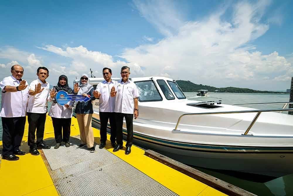 Fadhlina (tiga dari kanan) menyerahkan replika kunci bot kepada Guru Besar Sekolah Kebangsaan Pulau Aman, Rohayu Ibrahim (tiga dari kiri) pada Majlis Penyerahan Bot kepada Sekolah Kebangsaan Pulau Aman, pada Sabtu. Foto Bernama