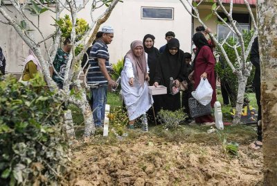 Ibu petugas JKR, Fatimah Walad, 70 ,menabur bunga di pusara anak bongsunya, Allahyarham Muhammad Ikram selepas selamat dikebumikan di Tanah Perkuburan Islam, Masjid Ar Rahman, Melele, Kodiang hari ini. Foto Bernama