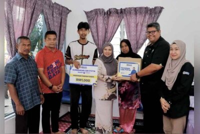 Norliza (tengah) dan Muhammad Muhsin (dua dari kanan) menyampaikan replika kad sumbangan Simpan SSPN dan kotak makanan kepada penerima sumbangan.