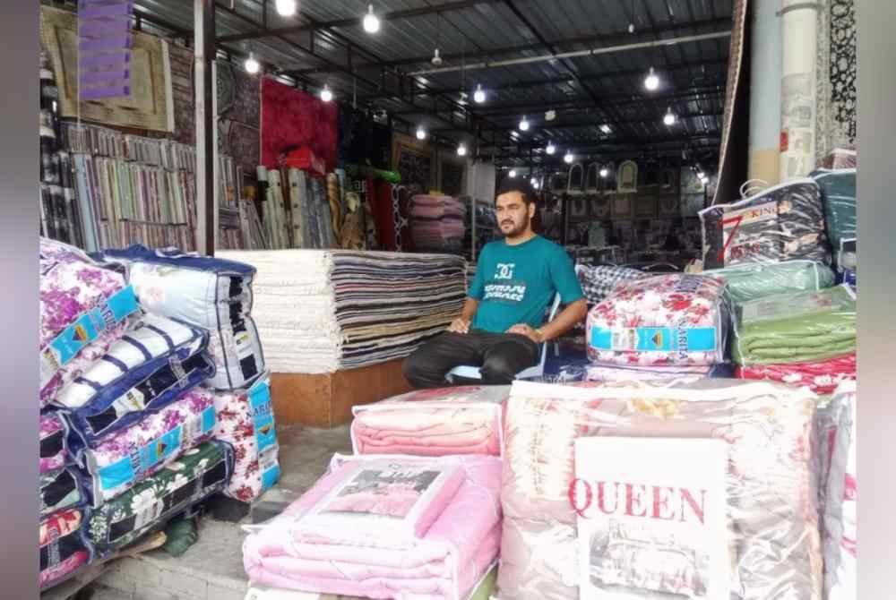 Amir duduk di hadapan kedainya menanti kehadiran pelanggan di premisnya.