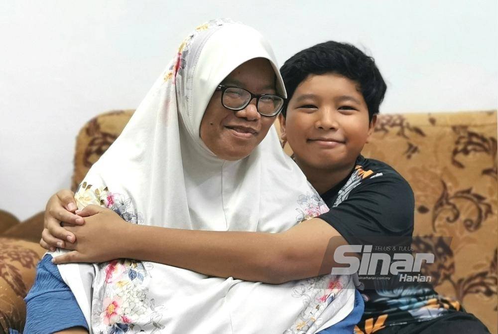 Iman memeluk erat ibunya, Ramlah ketika ditemui di rumah mereka di Kampung Bukit Kulim, Pengkalan Berangan.