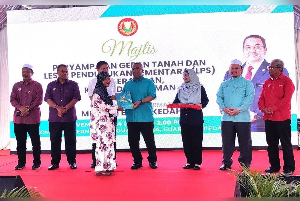 Muhammad Sanusi (tengah) menyampaikan geran dan LPS kepada penerima bagi daerah Yan di pekarangan Kompleks Guar Utama pada Sabtu.