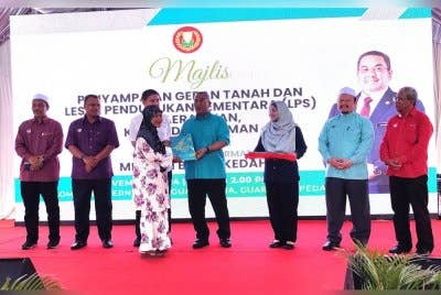 Muhammad Sanusi (tengah) menyampaikan geran dan LPS kepada penerima bagi daerah Yan di pekarangan Kompleks Guar Utama pada Sabtu.