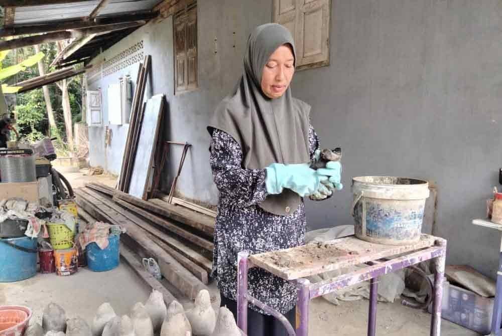 Noraini memasukkan bancuhan simen ke dalam stoking.