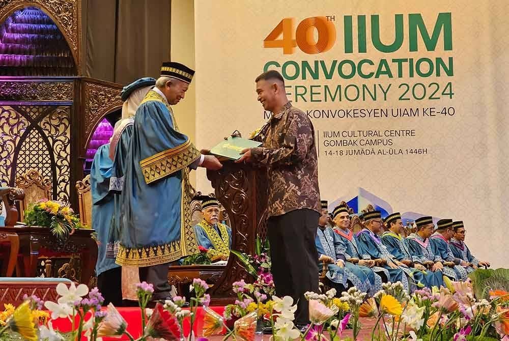 Amran mewakili arwah anaknya mengambil skrol yang disampaikan oleh Samsudin pada sidang Konvokesyen UIAM di Gombak.