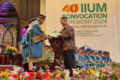 Amran mewakili arwah anaknya mengambil skrol yang disampaikan oleh Samsudin pada sidang Konvokesyen UIAM di Gombak.