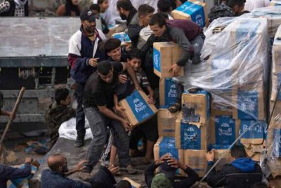 Penduduk Palestin yang kelaparan menyerbu trak bantuan selepas ia melintasi sempadan Rafah ke Gaza pada Disember 2023. - Foto Agensi